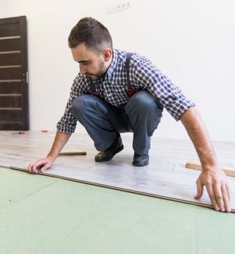 Young worker laying a floor with bright laminated flooring boards